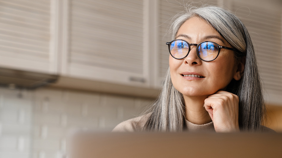 Women with glasses looking into the distance while sat at the computer