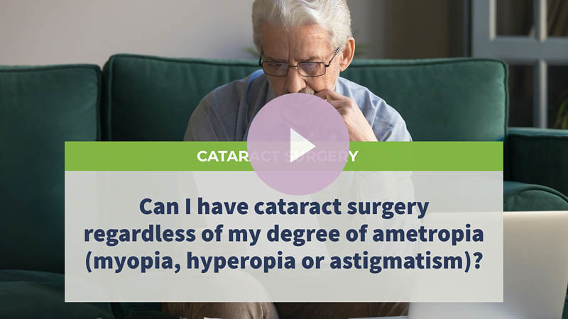 An old man with glasses sits on a sofa, looking at his laptop.