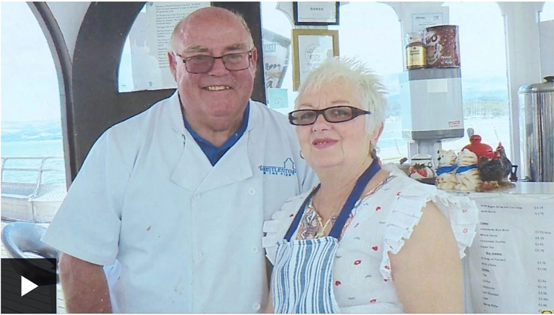 A portrait of a senior couple wearing chef outfits and aprons.