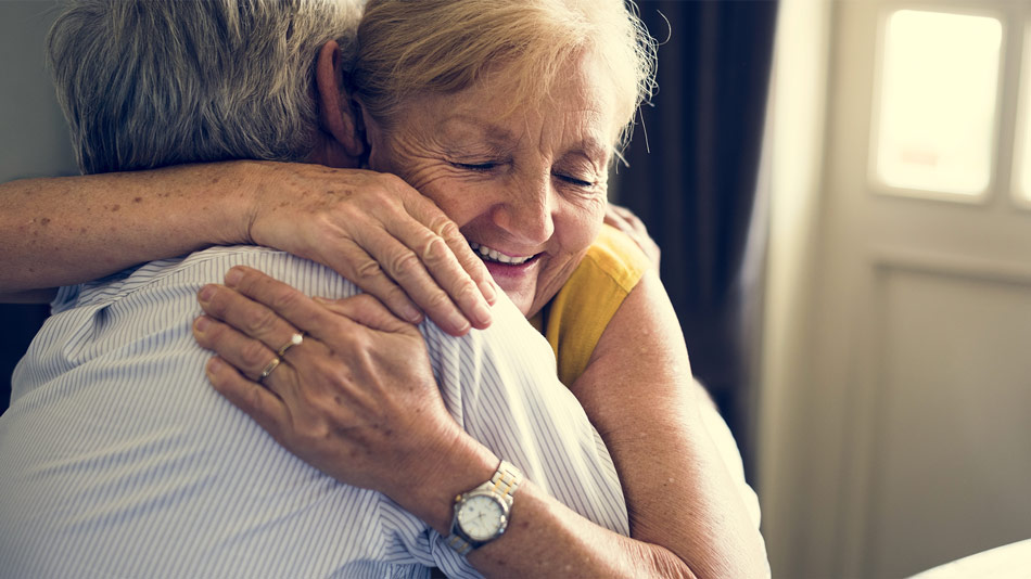 Senior woman happily hugging her partner after cataract surgery.